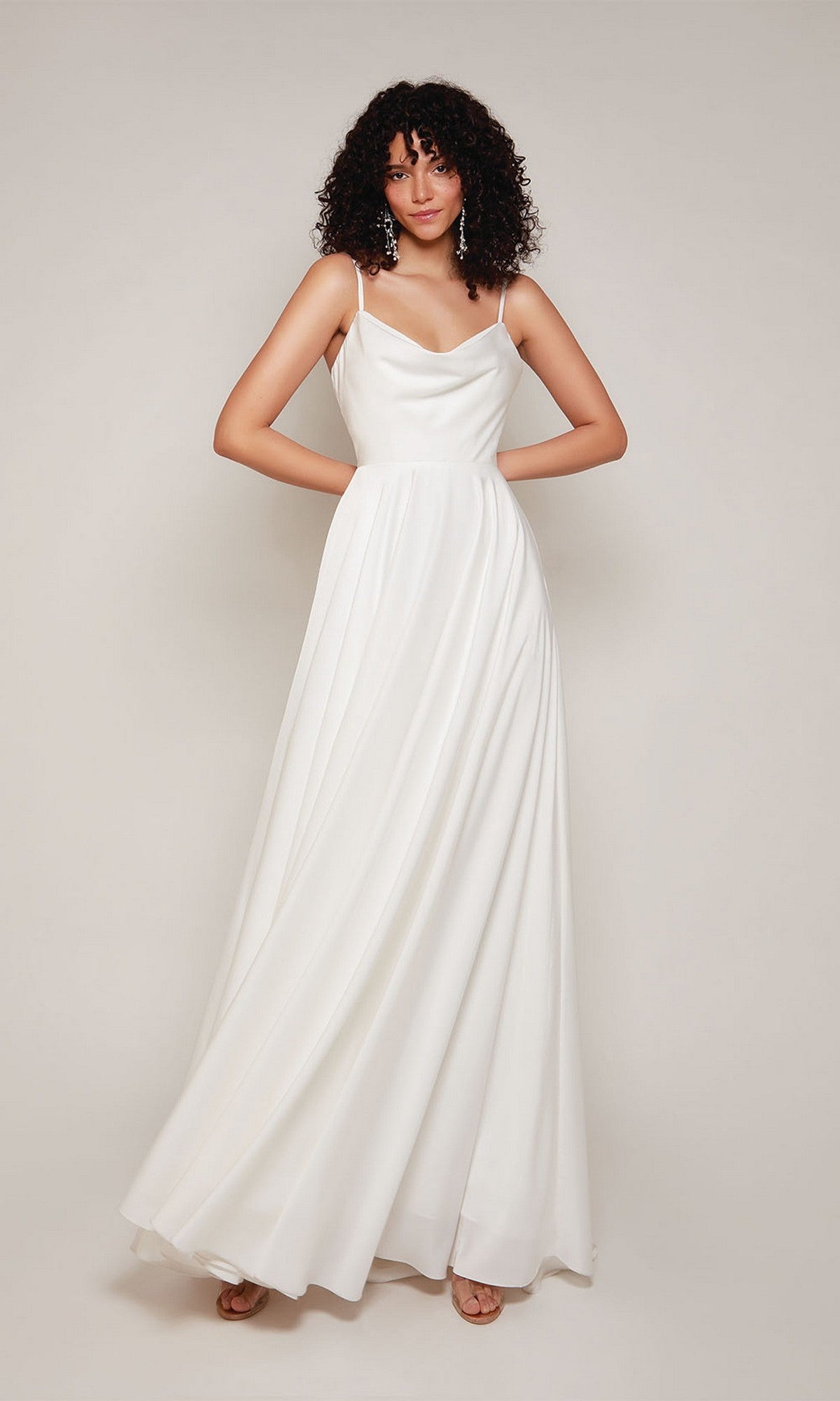 A woman with curly hair models the Alyce 7100 long formal dress—a sleeveless white satin gown with a draped cowl neckline and floor-length skirt—against a plain light background.